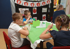 Trójka uczniów siedzi przy stoliku. Dzieci jedzą ciasta z kawiarenki.