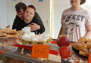 Trójka uczniów stoi przy ladzie wypełnionej ciastami.