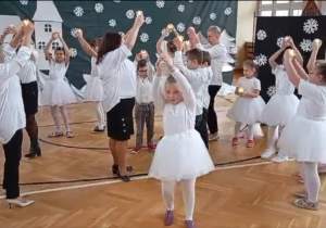 Na zdjęciu widoczni są uczniowie wraz z nauczycielami wykonujący taniec. W rękach trzymają świeczki.