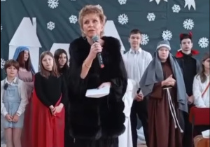 Na zdjęciu widoczna jest przemawiająca Pani Dyrektor, a za nią stoją uczniowie występujący w jasełkach.