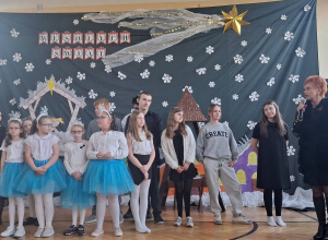 Grupa dzieci stojąca na tle dekoracji Jasełkowej