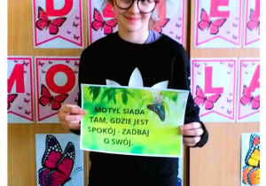 Zdjęcie przedstawia uczennicę trzymającą kartkę z napisem.